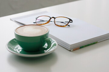 Latte art heart, green coffee cup on white table.
