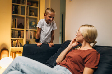 Obraz premium Young Caucasian boy coming to talk to his mother while she is having a phone call.