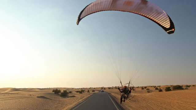 Car, motorcycle and paramotor on desert road of Dubai 