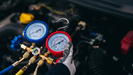 Close up hand of Mechanics inspect and check the refrigerant and fill the car air conditioner. Worker service car air conditioner.