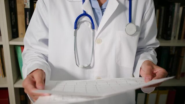 Doctor reviews cardiac probes and electrograms in her medical attire within her office. 
