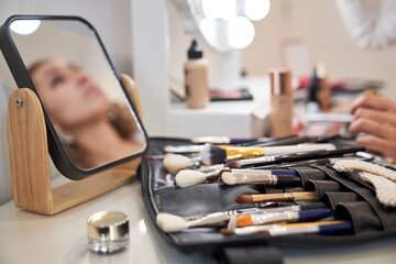 Set of makeup professional brushes and mirror placed on table