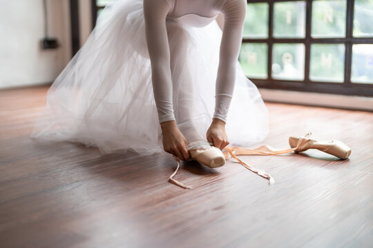 Ballerina in ballet shoes. Asian girl tying ribbons of toe shoes. ballet dancer preparing and wearing ballet shoes in dance studio prepares for a rehearsal.