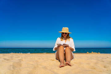 Woman sitting on beach reading book
