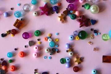 Various colorful beads on bright pink background. Top view.