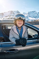 Smiling boy leaning out car window on winter day