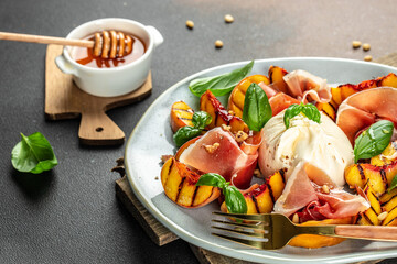 Salad with grilled peaches, mozzarella, prosciutto ham, basil, for wine. top view. place for text