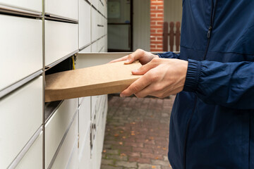 A man with a box in his hands near the self-service mail terminal. Parcel delivery machine. Person holding a cardboard box. Mail delivery and post service, online shopping, e commerce concept