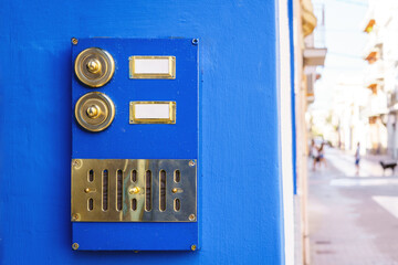 Vintage gold-colored doorbell on the door of apartments with blue facade