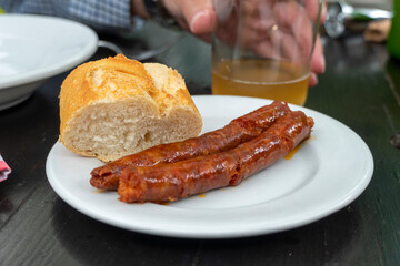 Tapa of chistorra two fried chorizos with bread on plate Basque country Spain