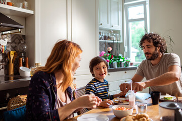 Young Caucasian family having breakfast together in the morning in the kitchen at home