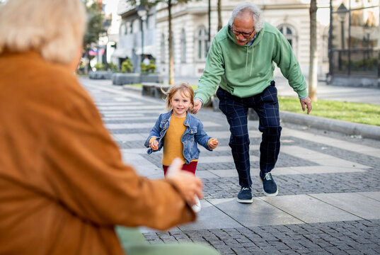 Caucasian grandparents having fun with their granddaughter at the pedestrian zone in the city