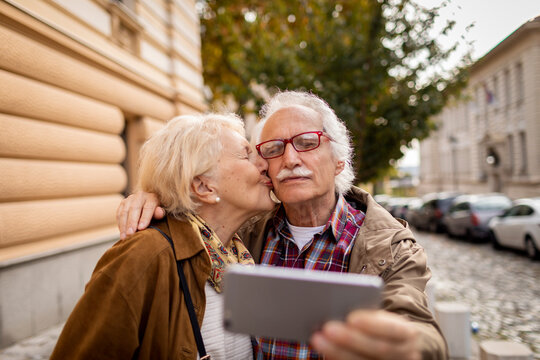 Senior Caucasian taking a selfie on smartphone while on date in the city