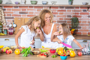 Mother and daughters cooking together in the kitchen. Healthy food concept. Portrait of happy family with fresh smoothies. Happy sisters.