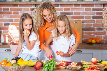 Mother and daughters cooking together in the kitchen. Healthy food concept. Portrait of happy family with fresh smoothies. Happy sisters.