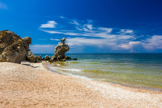Rocks and stones of unusual bizarre shape on the sandy seashore at clear day, shells