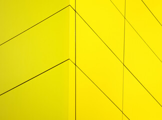 Close-up of vibrant yellow facade. Its minimalist design features rectangular panels that cover the...