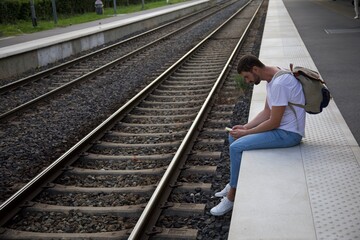 Man using his smartphone while waiting at train station