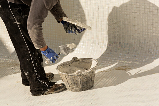 Obrero colocando gresite en una piscina en construcci&oacute;n.