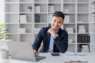 Young committed asian businessman sitting working with a laptop computer in the office.