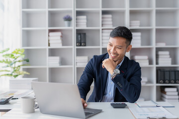 Young committed asian businessman sitting working with a laptop computer in the office.