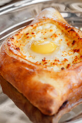 Adjarian khachapuri with raw egg, side view, selective focus, vertical frame.