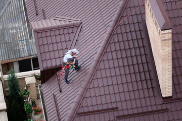 The master carries out maintenance and restoration of metal profiles for the roof.