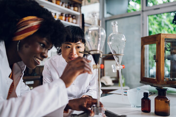 Two happy pharmacy workers are using a funnel for cure making