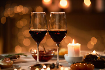 Close up of two wine glasses on dinner table with Christmas lights in background, copy space