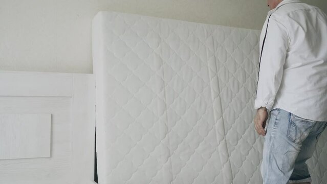 A man cleans a mattress with a steam cleaner. Heat treatment and cleaning from dirt and insects of bedding.