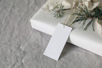 Christmas present. Empty gift tag, label mockup. Handmade gift wrapping with cotton paper, pine...