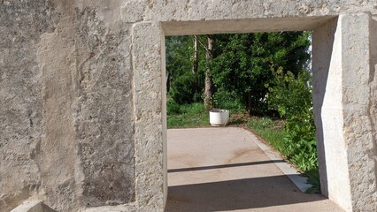 A window opening without it in the old wall, through which you can see the garden and courtyard