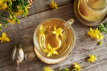 Fresh St. John's wort flowers in a cup of herbal tea, top view - obrazy, fototapety, plakaty