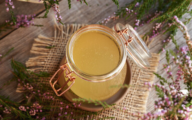 A jar of herbal syrup with blooming wild heather plant