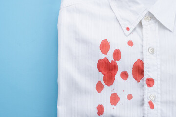 A drops of blood a white shirt. Stained clothing. Cleaning concept. top view. 