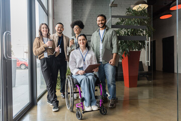 Portrait of diverse startup team looking at camera and posing in office, wheelchair user, inclusion