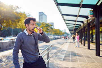 latin american man commuter drinking coffee at bus stop