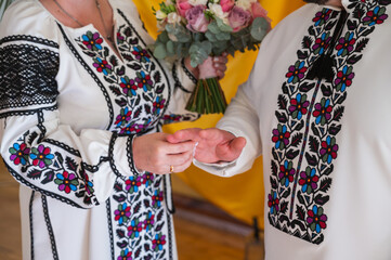 close-up view of a young couple holding hands in embroidered traditional Ukrainian clothes