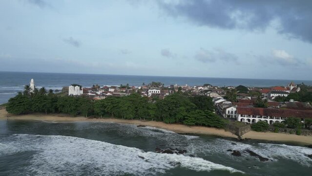 cinematic aerial footage as the camera gracefully moves around to reveal the renowned Galle Fort, an ancient fortress and iconic lighthouse landmark situated by the Indian Ocean in Galle, Sri Lanka
