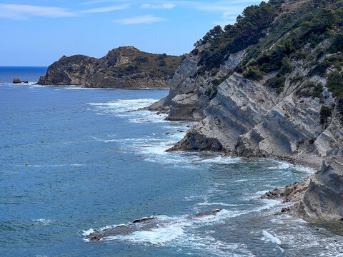 Scenic view of the unique flysch rock formations and dramatic cliffs meeting the blue ocean waves along the Basque Coast Geopark in Zumaia, Spain. Beautiful coastal nature landscape.