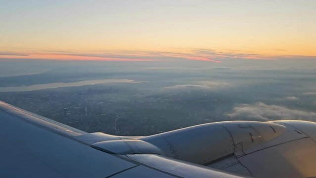 Airplane flying over Istanbul, Turkey with Istanbul city skyline in window with sunset view in orange.