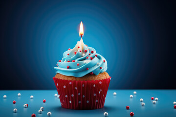 A delicious cupcake with blue frosting and a lit candle, perfect for birthdays and celebrations.