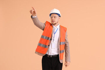 Male architect in vest pointing at something on beige background