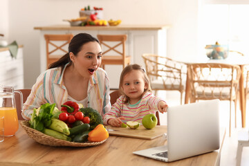 Little girl with her mother eating apples in kitchen