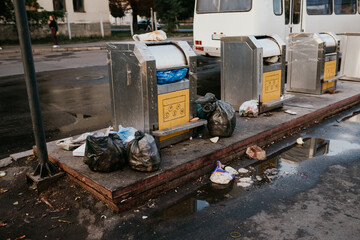 Overflowing trash cans polluting a street in the city