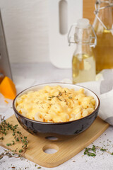 Bowl of tasty Italian pasta with Cheddar cheese on light background