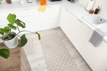 Stylish rug on floor in light kitchen