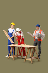 Team of male builders with wooden planks and house plans on green background