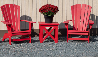 Red Adirondack chairs with flowers on table