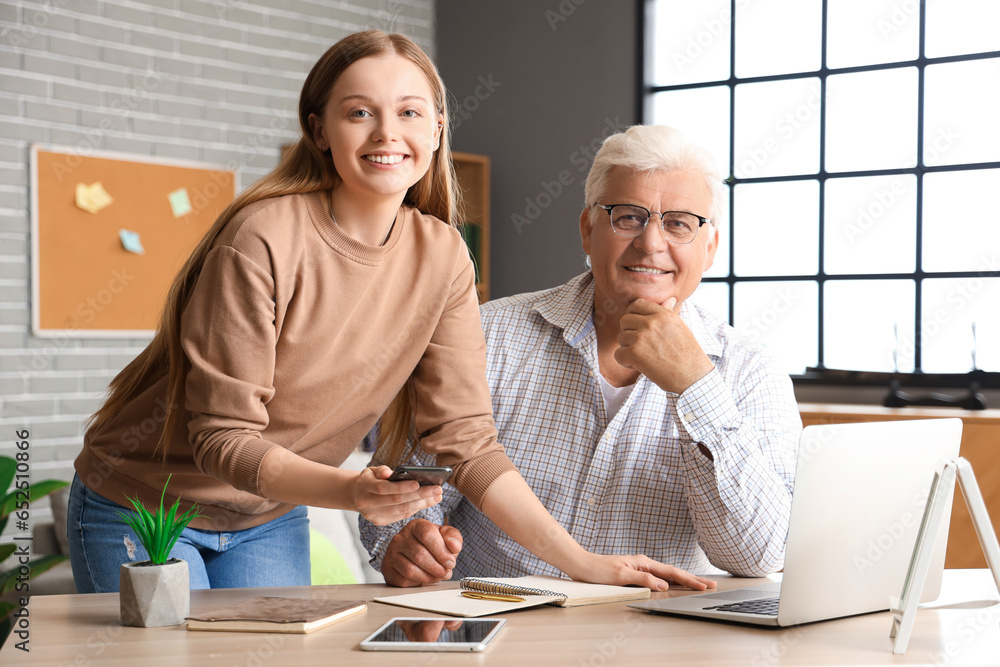 Poster Senior man with his granddaughter using laptop at home